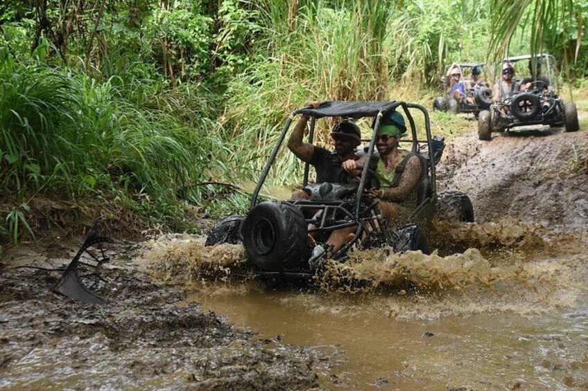 Off-road vehicles navigating a muddy terrain with vegetation on the sides. 2