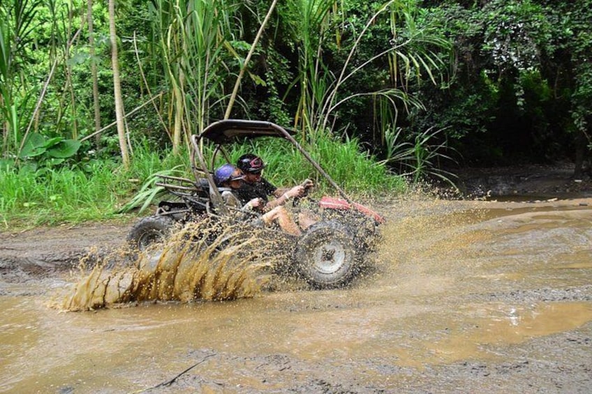 A person driving a red ATV through a muddy stream. 2