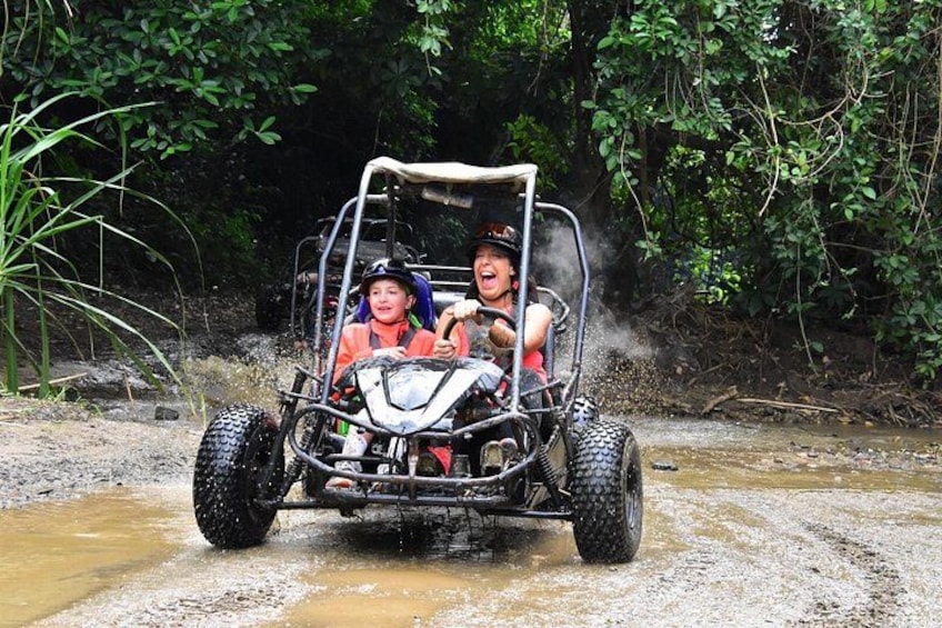 A person driving a vehicle through a muddy area with water. 1