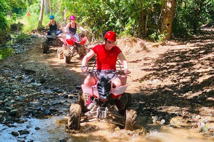 People riding quad bikes on a rocky path in a forested area. 5