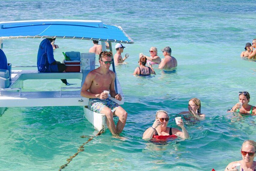 A boat with people in the water, a clear blue sea, and a person sitting on the boat. 2
