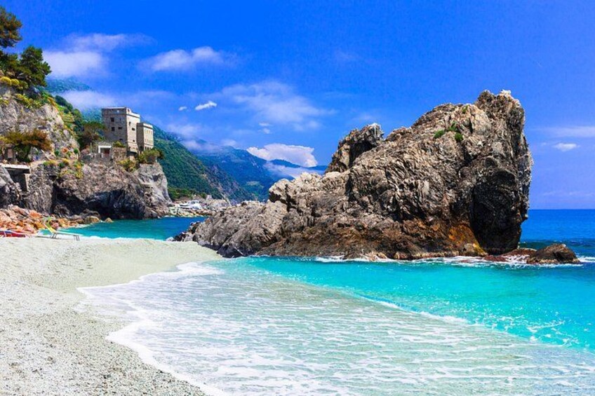 Una spiaggia con acque cristalline color turchese, una grande formazione rocciosa e un edificio a picco sulla scogliera. 3