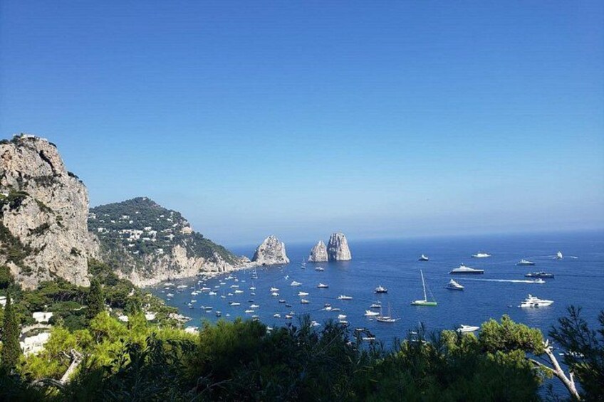 Un paisaje costero con acantilados rocosos, mar azul cristalino y numerosos barcos. 3