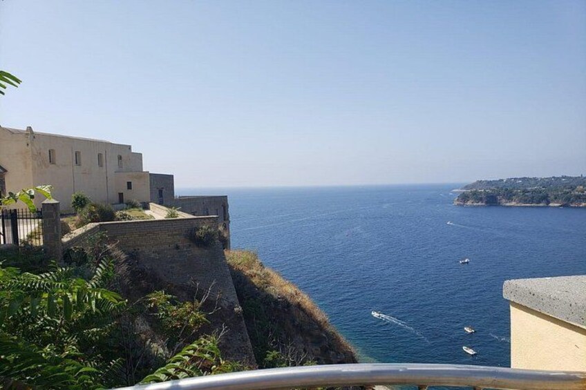 Vista costera con un edificio sobre el mar, cielo despejado y una masa de tierra a lo lejos. 5