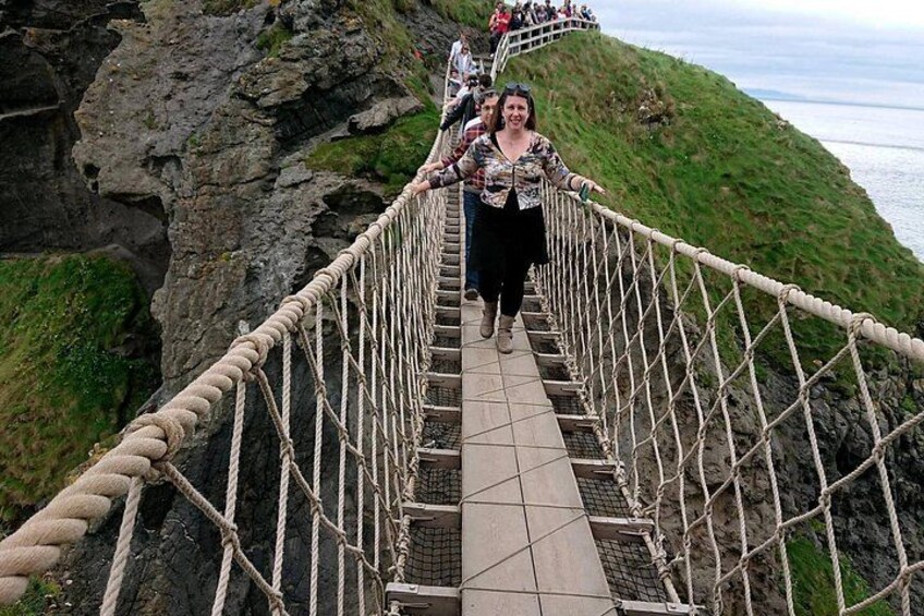 A rope bridge over a rocky cliff with a person walking on it. 1