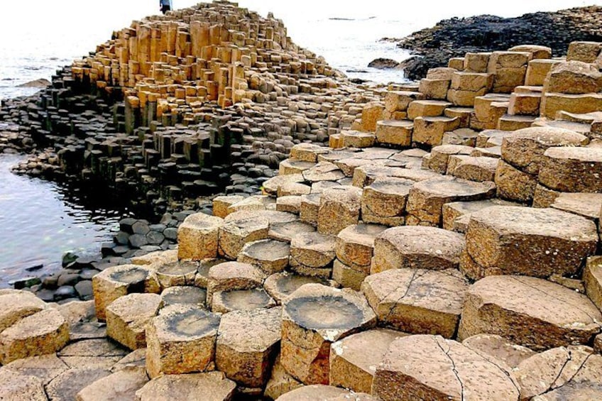 A large collection of hexagonal stone structures by the water. 2