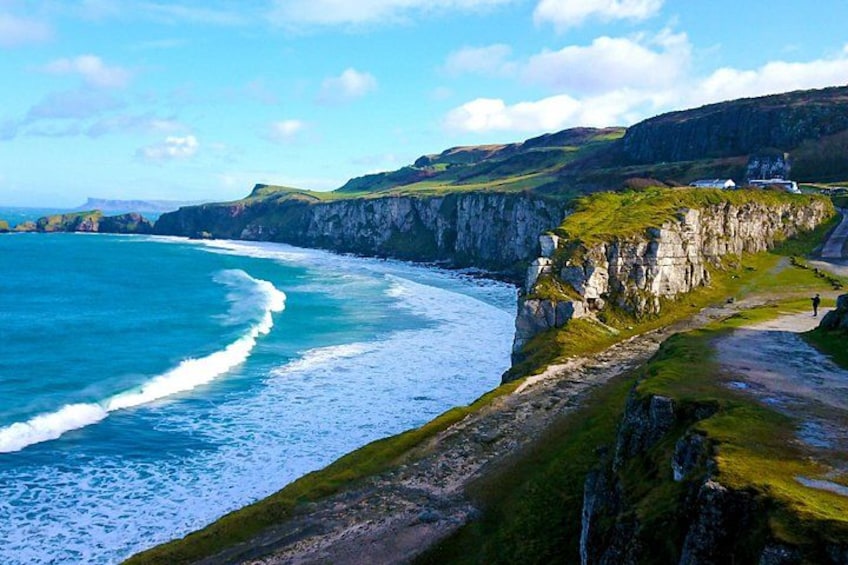 A coastal landscape with cliffs, a beach, and a path. 4