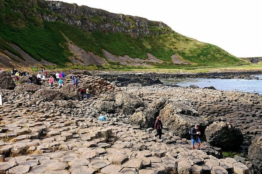 A rocky coastal area with people walking on the stones. 5