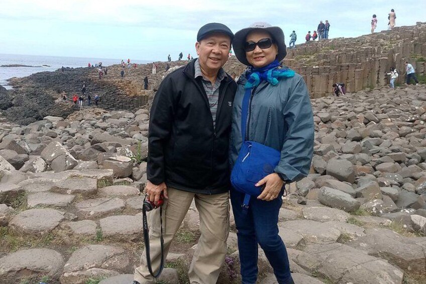 A rocky coastal area with people walking on the rocks and a few standing on a higher platform. 1