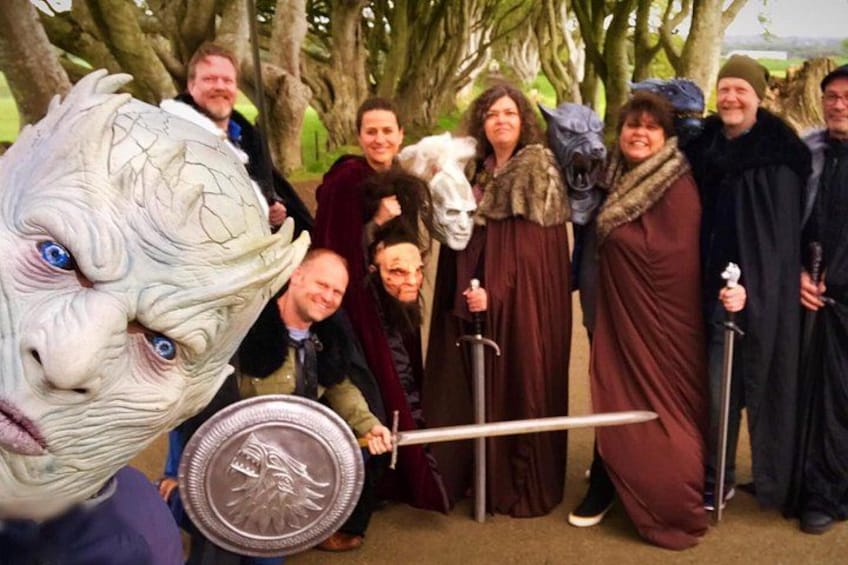 A group of people in historical costumes with a large statue of a horse's head and a shield. 1