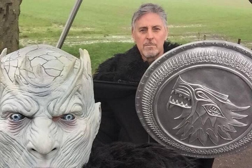 Una persona sosteniendo un escudo con diseño de lobo y una cabeza de piedra tallada. 5