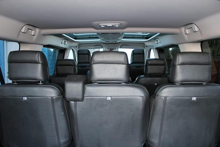 The interior of a vehicle with black leather seats and a sunroof. 2