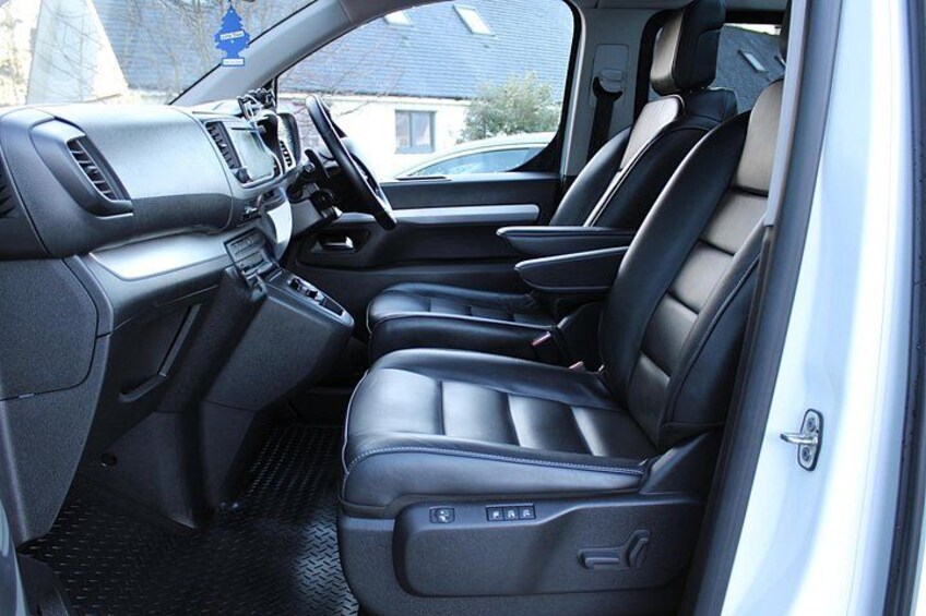 L'intérieur d'une voiture, avec des sièges en cuir noir, une console centrale et un levier de vitesses bien visible. 4