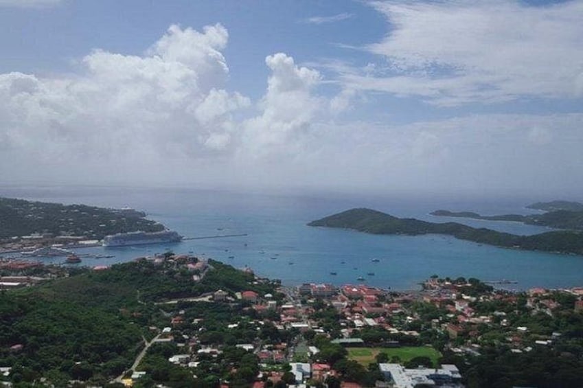 A coastal town with buildings, a harbor, and islands in the distance. 1