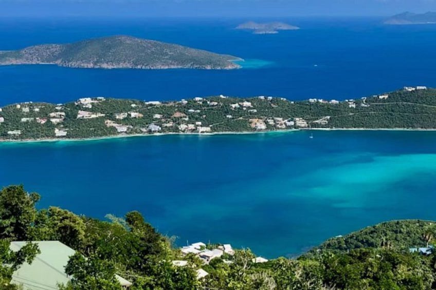 A coastal landscape with a clear blue sea, a small island with buildings, and lush greenery. 3