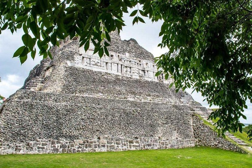 A large stone pyramid with a stepped structure, surrounded by a grassy area and trees. 3