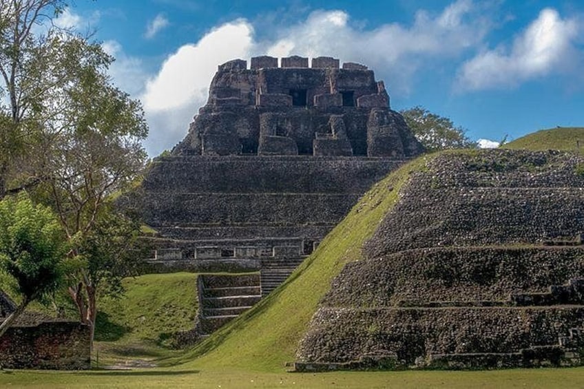 A large ancient pyramid with a staircase leading up to it, surrounded by greenery and trees. 4