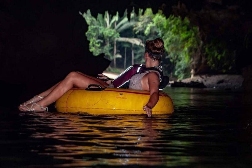A person floating on a yellow inflatable tube in a body of water at night. 2