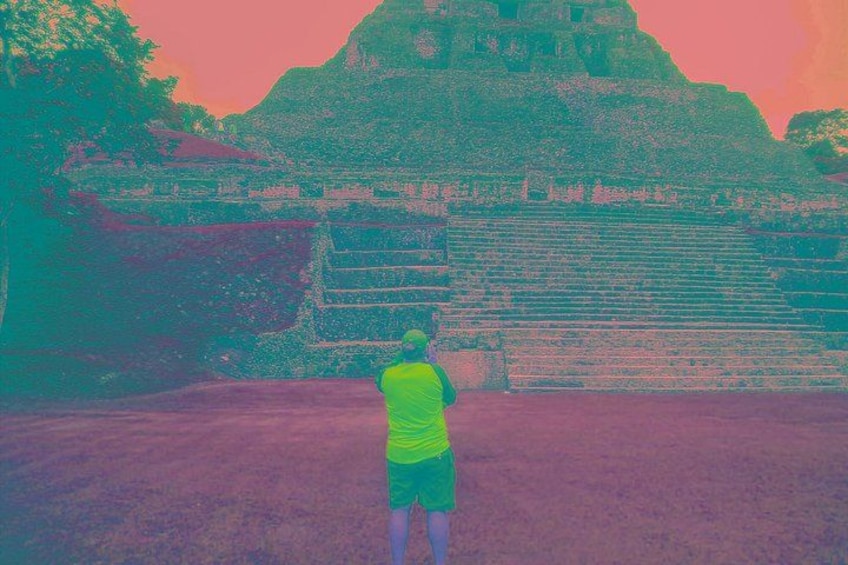 A person standing in front of a large, ancient stone structure with steps leading up to it. 5