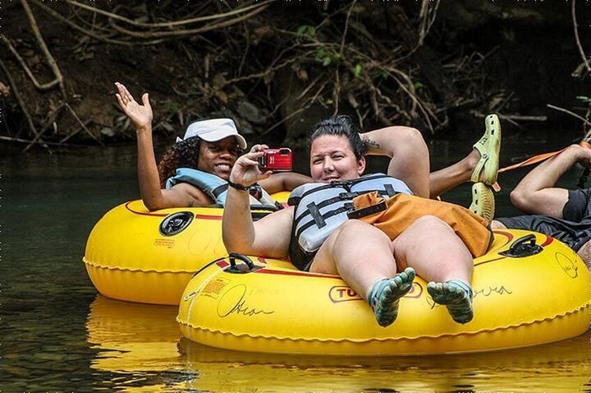 Two people on yellow inflatable rafts in a river surrounded by dense vegetation. 1