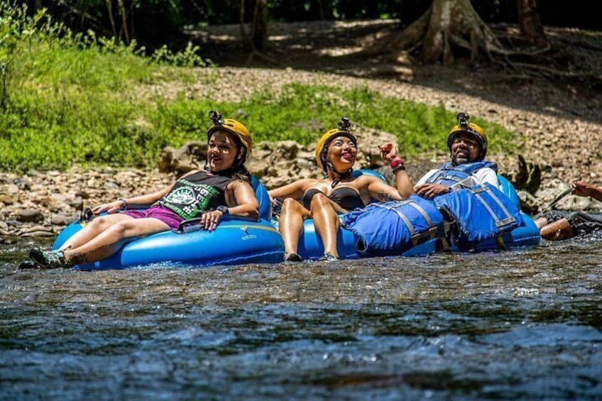 Tres personas en una balsa azul flotando en un río rodeado de follaje. 4