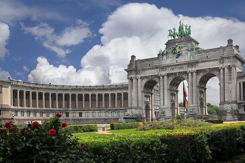 A grand archway with statues, surrounded by well-maintained gardens and a clear sky. 3