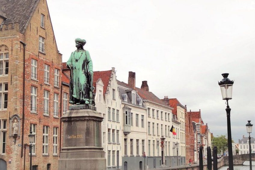 A statue of a historical figure on a pedestal, a canal with a bridge, and traditional European buildings. 4