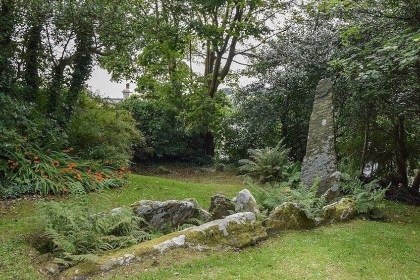 A garden with a stone structure, lush greenery, and a small stream. 5