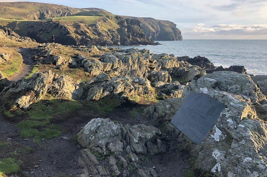 Rugged coastal terrain with rocky outcrops and a cliff overlooking the sea. 3