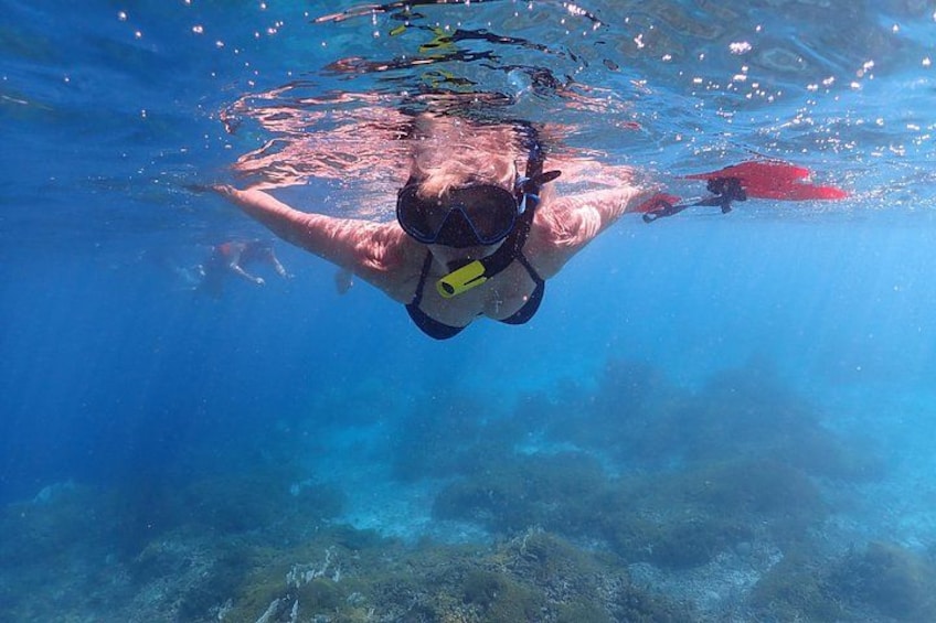 A person underwater with a snorkel and fins, swimming in clear blue water. 2