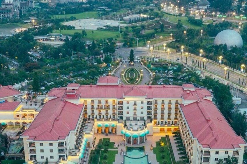 A large building with a red roof, surrounded by greenery and a circular park. 3