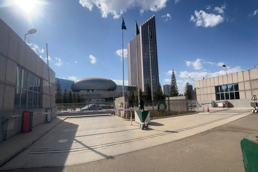Un edificio moderno con fachada de vidrio circular, un rascacielos alto y un cielo azul despejado. 5