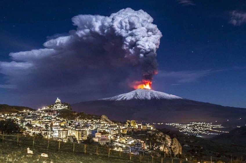 A volcano erupting at night with a town in the foreground. 1