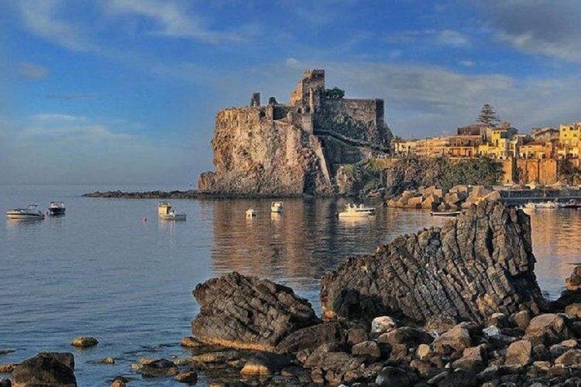 A coastal town with a historic castle, calm sea, and rocky shoreline. 4