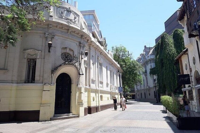 A historic building with ornate architecture, a paved street, and a clear blue sky. 1