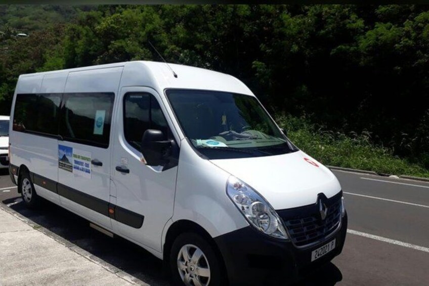 A white van parked on a road with greenery in the background. 2