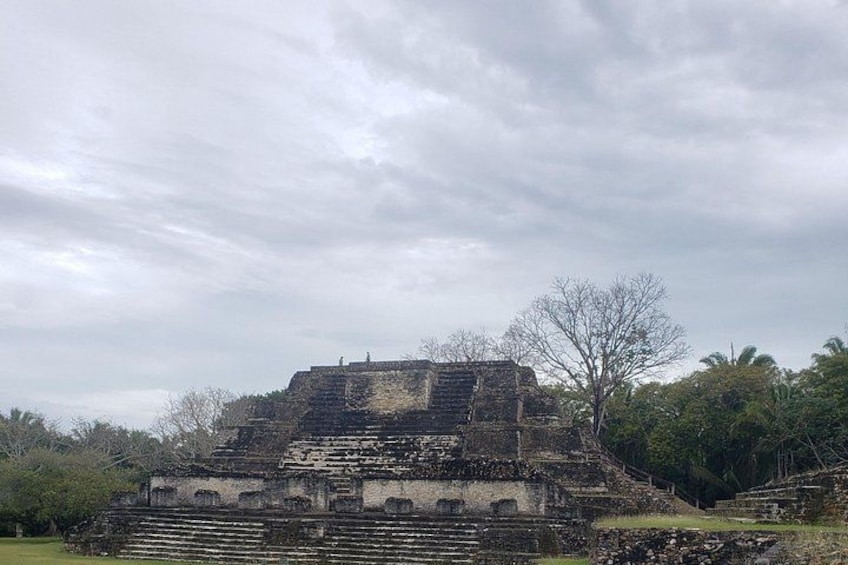 An ancient stone structure with steps leading up to it, surrounded by trees and greenery. 4