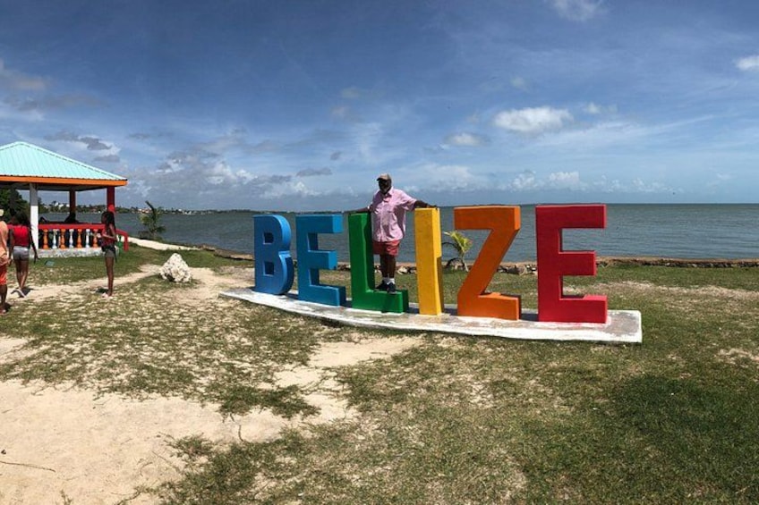Une plage avec de grandes lettres colorées qui épellent le mot « BELIZE », et une personne debout sur ces lettres. 2