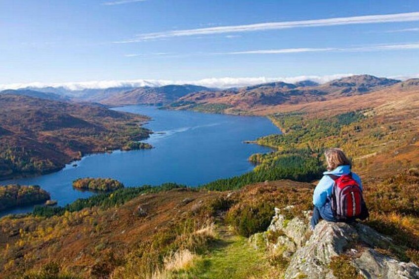 A person sitting on a rock overlooking a lake surrounded by hills. 3