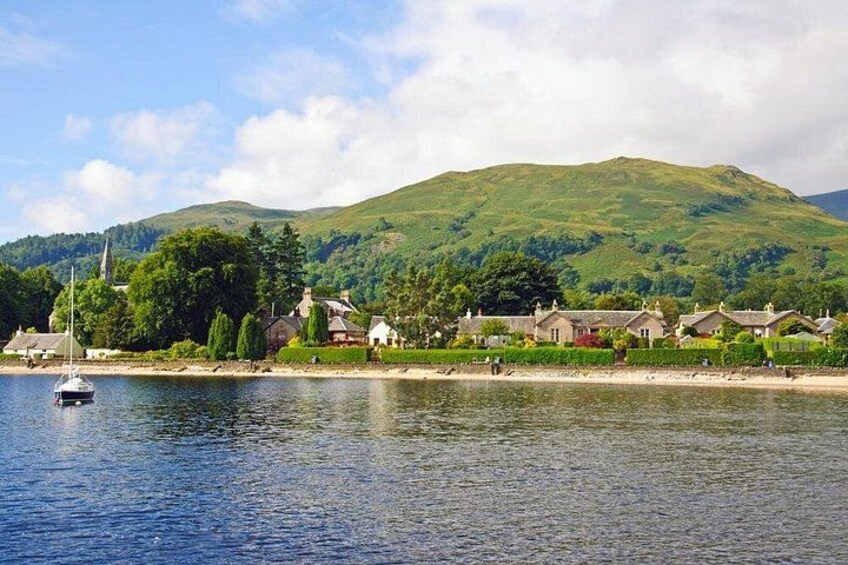 A coastal village with houses, a church, and a hill in the background. 1