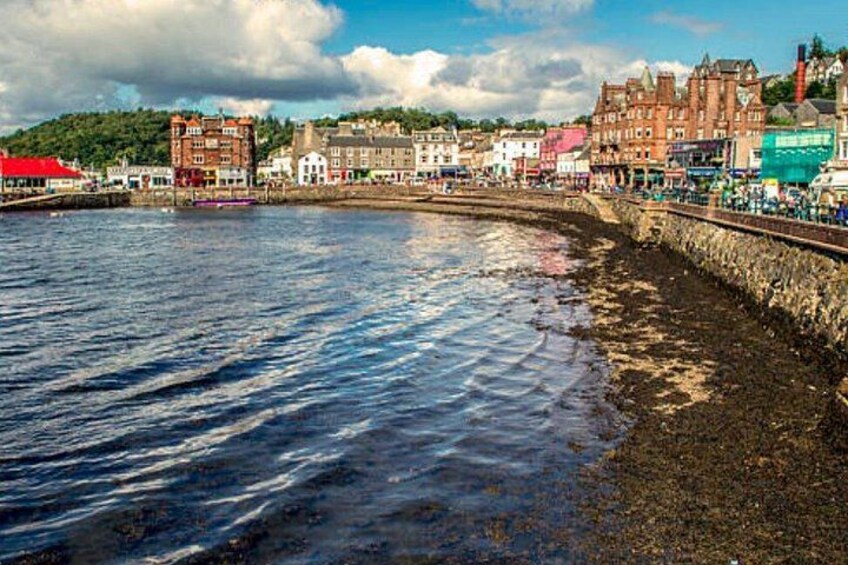 A waterfront with buildings, a stone wall, and a clear sky. 3