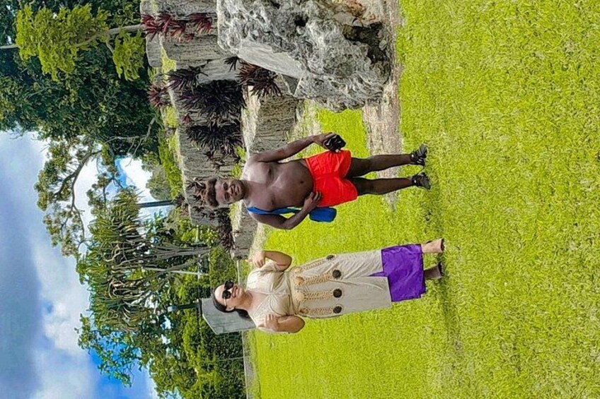 Two people standing on a grassy field with trees and rocks in the background. 5