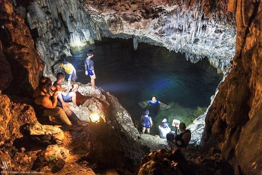 A group of people exploring a cave with stalactites and stalagmites. 4