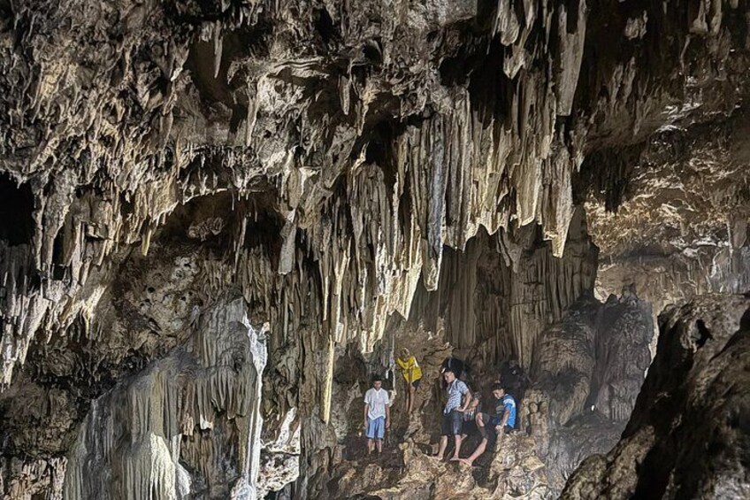 A cave with stalactites and stalagmites, people exploring the cave. 2