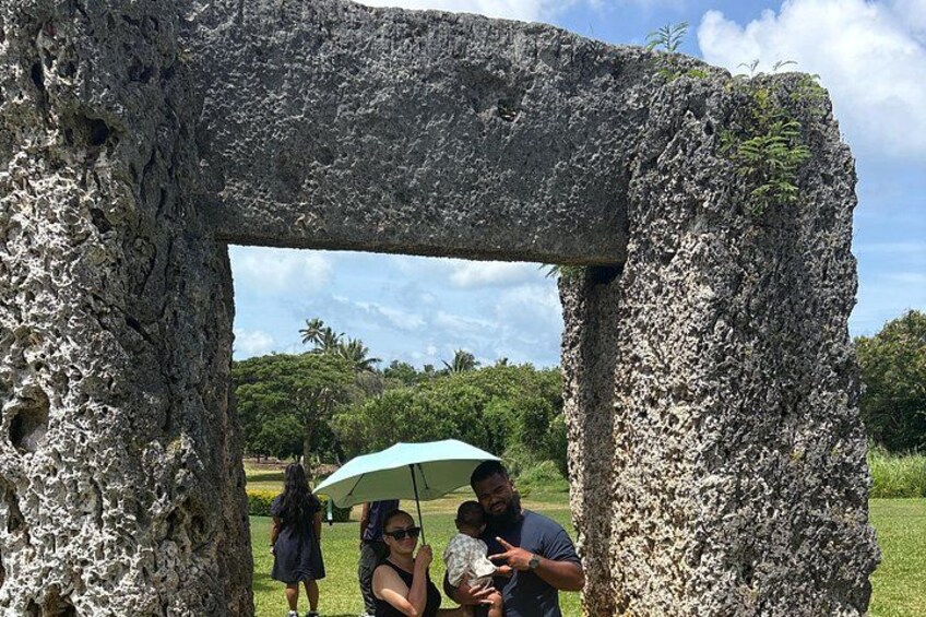 A large stone structure with a natural archway, surrounded by greenery and trees. 3