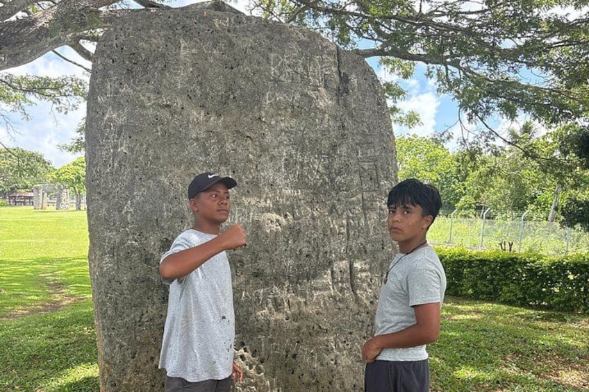 Two individuals standing next to a large tree in a park. 4