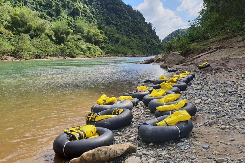 A riverbank with several black and yellow inflatable rafts lined up on the shore. 2
