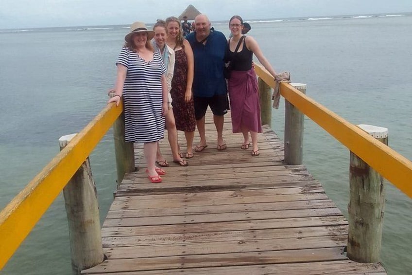 Un grupo de personas de pie sobre un muelle de madera con barandillas amarillas. 1