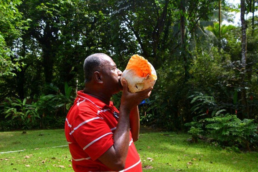Un hombre con camisa roja bebiendo de un recipiente naranja grande al aire libre. 4