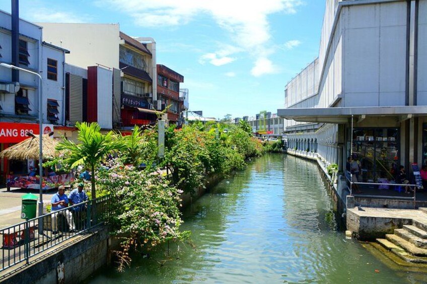 Un canal bordeado por edificios, un puente y abundante vegetación. 3